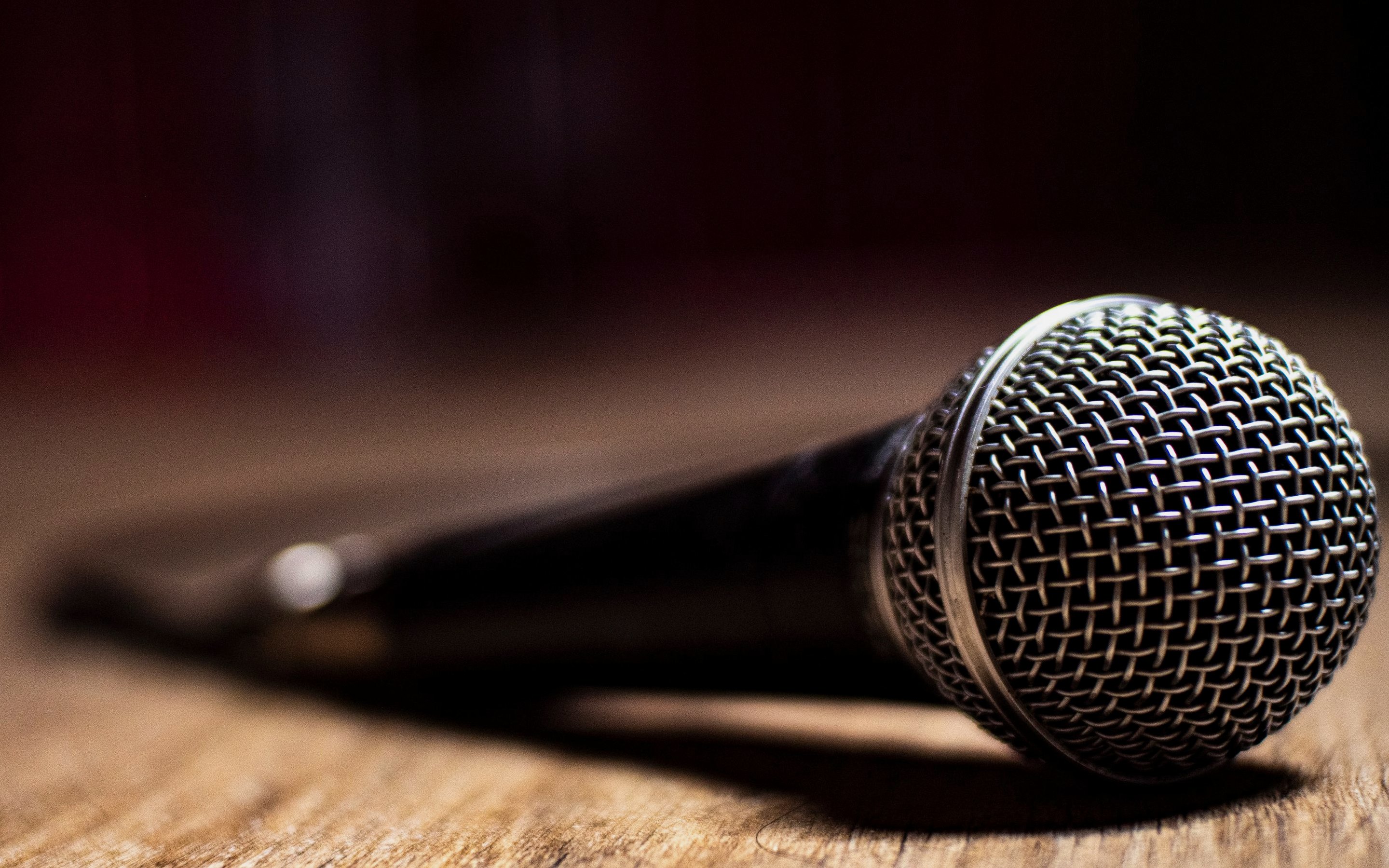 A microphone lying on a worn wooden table in low light.