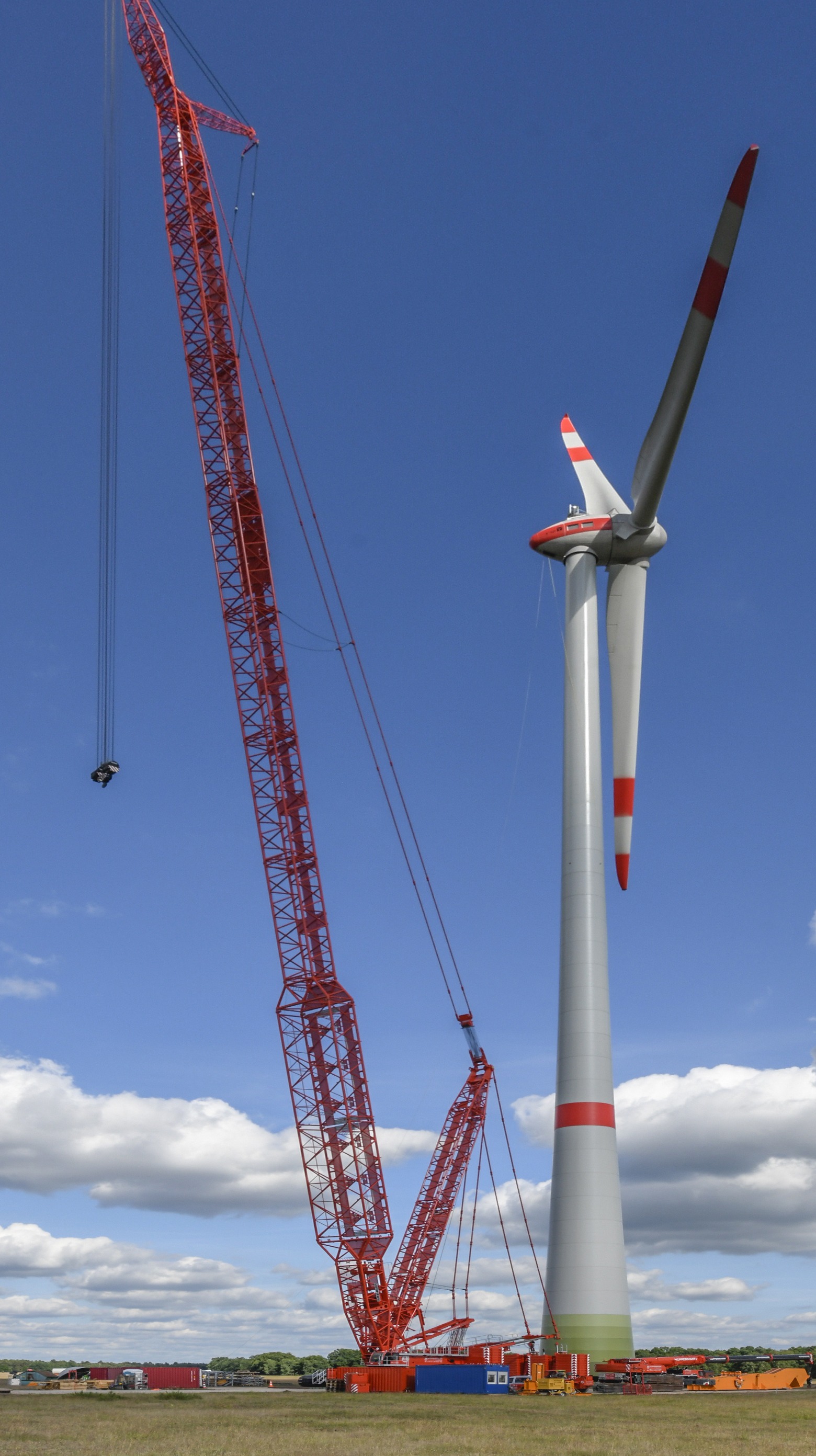 A crawler crane beside a wind turbine on a work site — the planned take-down, not a lonely silhouette.
