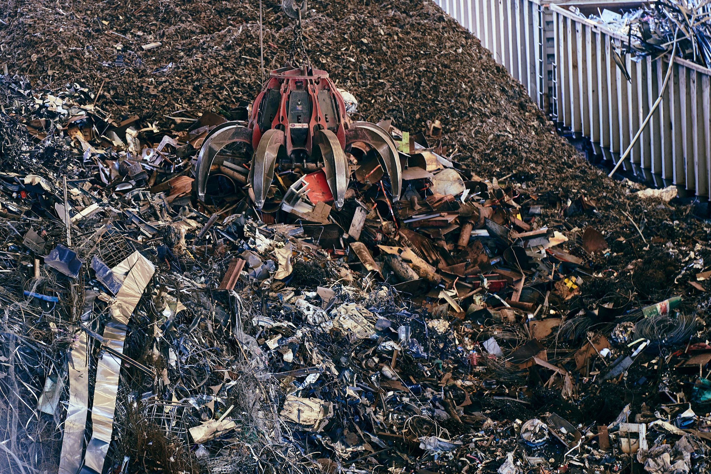 A claw grab lifting scrap metal in a recycling yard.