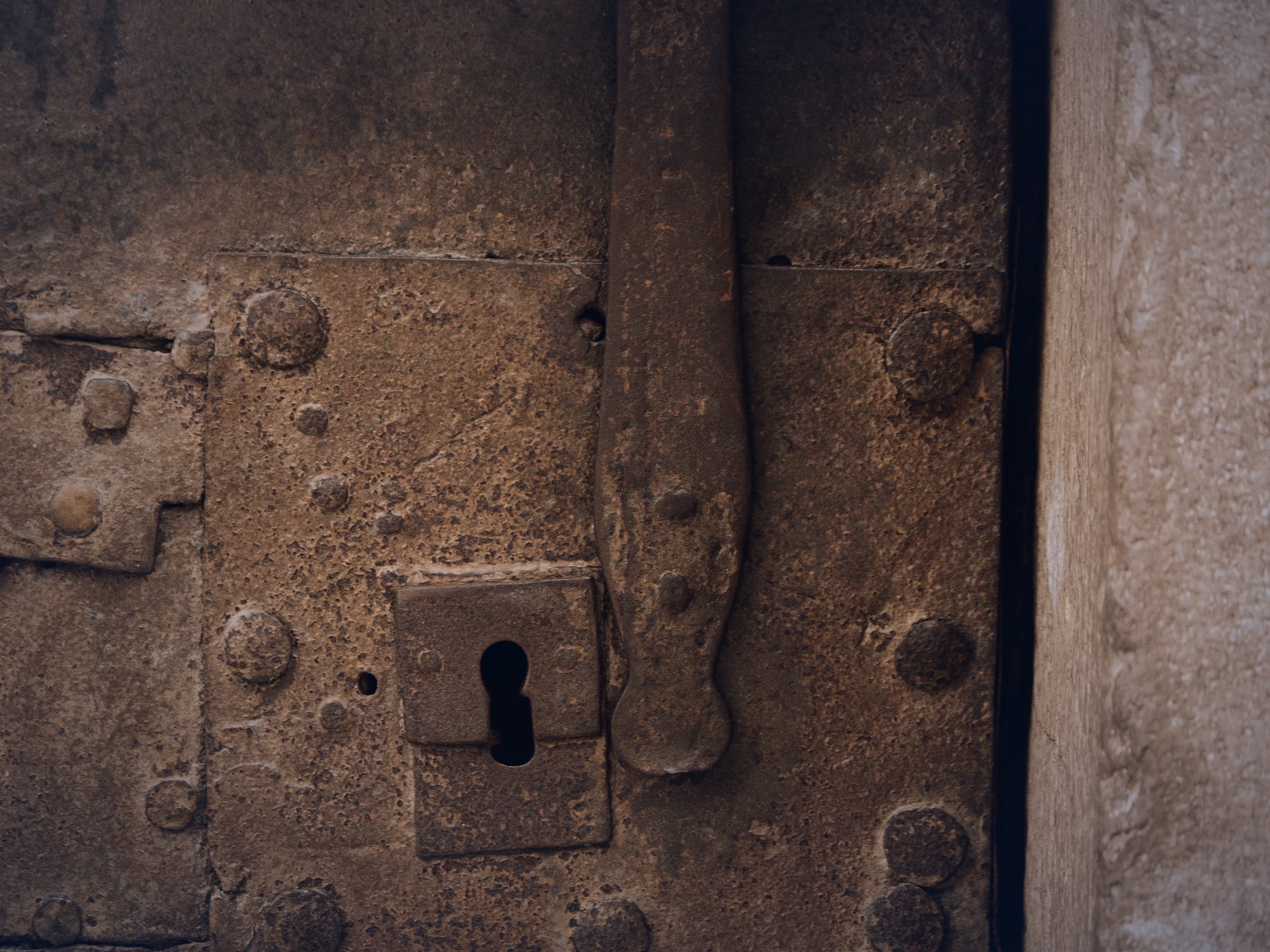 An old Spanish door, bolted shut, with an empty iron keyhole.