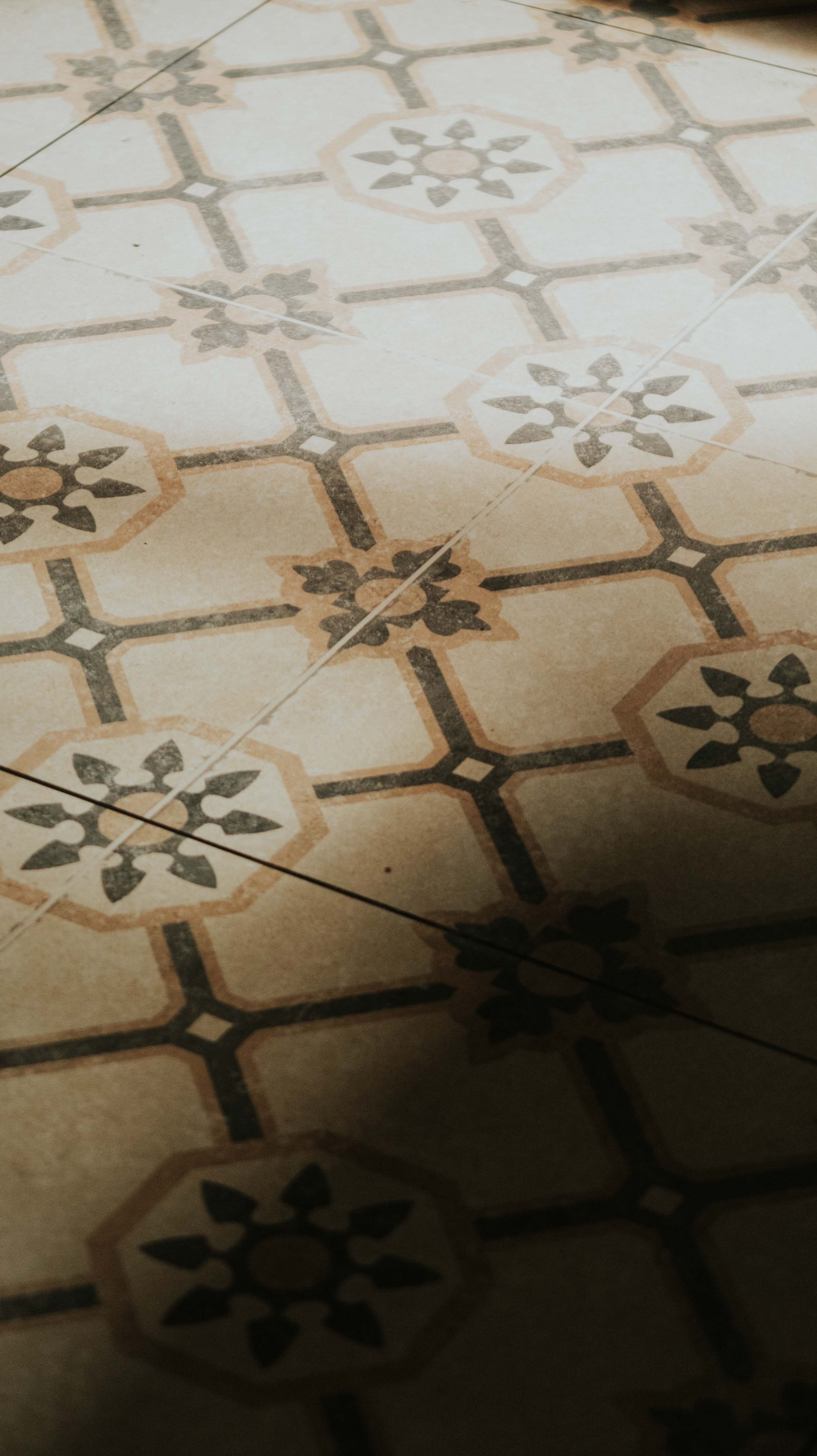 An old patterned tile floor, hand-laid, with afternoon shade falling across it.